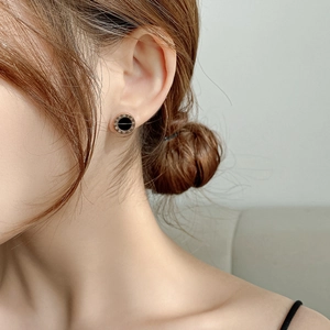 Close-up of rose gold stud earring featuring black inlay and roman numeral engravings