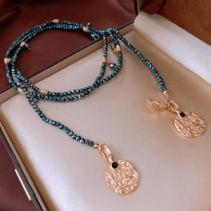 Close-up of vintage layered pearl necklace with dark blue beads and antique gold coins