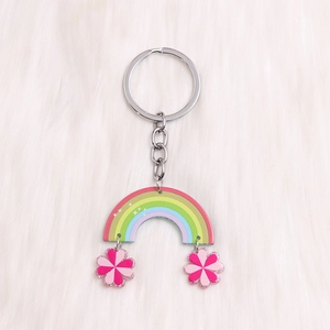 Détail d'un porte-clés arc-en-ciel et fleurs en acrylique sur fond en peluche blanc