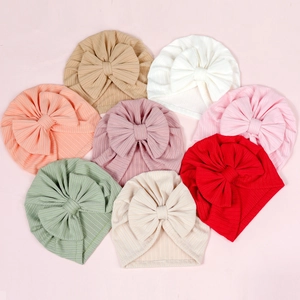 Flat lay display of colorful ribbed knit baby bow hats in eight vibrant pastel colors