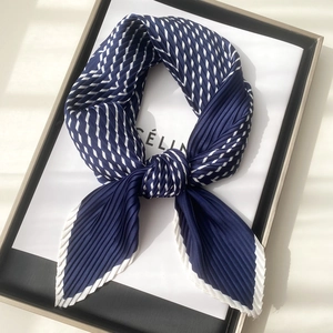 Detailed view of dark blue pleated silk scarf with white stripes and elegant texture