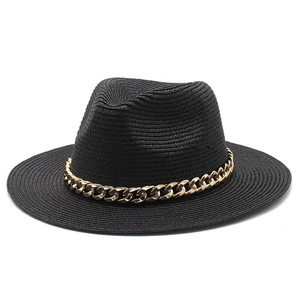 Detail view of a black straw fedora hat featuring a chunky gold metal chain link band