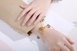 Close-up of golden stainless steel heart bracelet on wrist with engraved love mama charms