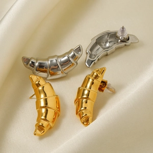 Detailed close-up of 18k gold and silver croissant dome hoop earrings on satin fabric