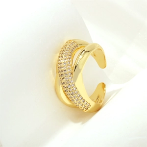 Macro shot of gold-plated X-shape cross ring with micro-pave zircons on fabric