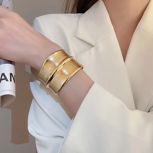 Détail d'un large bracelet manchette doré à vagues sur mannequin avec fini miroir poli