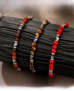 Detailed shot of three beaded bracelets with agate, tiger eye and metallic spacers on stand