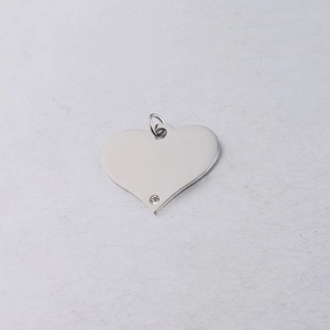 Macro detail of silver heart pendant with clear crystal accent on metallic surface