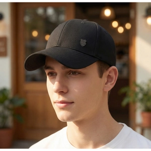 Detail of black baseball cap with metallic R-shaped shield badge on textured cotton fabric