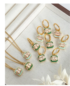 Detailed view of square champagne zircon necklace and earrings with enamel trim in a jewelry tray