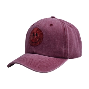 Close-up of a sequin smiley face patch on a vintage washed burgundy baseball cap