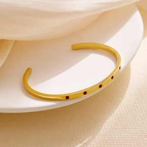Macro detail of 18k gold plated stainless steel cuff bracelet with red crystals
