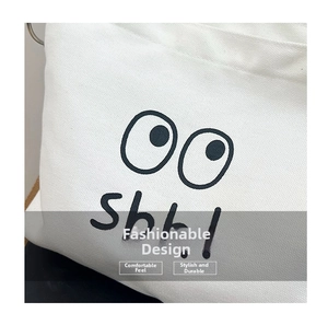 Close-up of white canvas fabric with black embroidered eyes and Shh! lettering detail