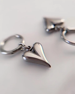 Macro dettaglio di un orecchino con ciondolo a cuore in argento lucido stile minimalista