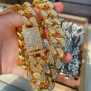 Macro shot of a gold-plated Cuban link chain featuring a luxury rectangle iced-out clasp