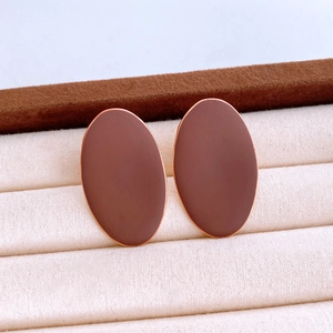 Macro detail of matte mocha oval stud earrings with gold trim in a beige velvet jewelry box