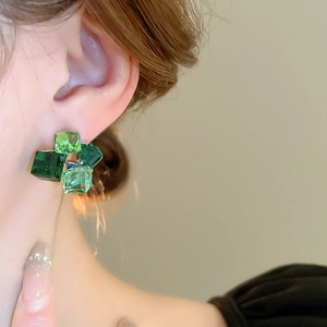 Dettaglio degli orecchini a cubo in cristallo verde indossati da una modella elegante