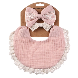 Pink cotton muslin baby bib and lace headband set displayed on cardboard packaging