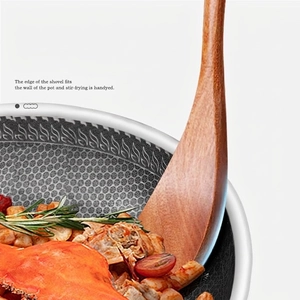 Natural teak wood spatula stirring meat and tomatoes in a honeycomb non-stick frying pan