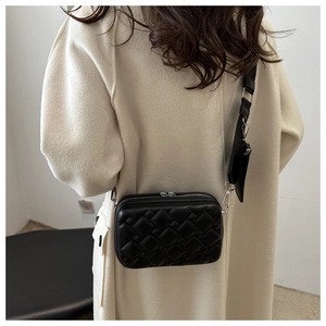 Detail of black quilted crossbody camera bag with wide strap and mini coin pouch