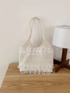 Detailed view of white tiered lace handbag with ruffle edges on a rustic wooden table