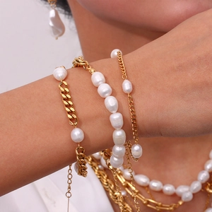 Detail of layered gold chain and pearl bracelet set showing exquisite craft and texture