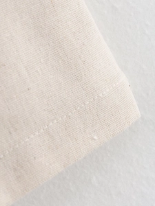 Macro shot of beige linen fabric texture and fine stitching on a casual two-piece set