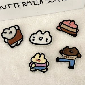 Macro view of five cute embroidered patches including cartoon bear, bunny and cat on plush rug