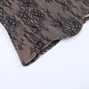 Macro detail of intricate black floral lace embroidery on light brown corset fabric