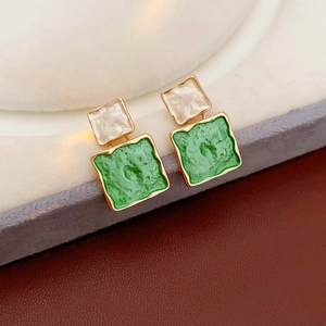 Détail des boucles d'oreilles carrées double couche avec texture vert émeraude et doré
