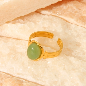 Detailed view of an 18K gold plated oval green stone ring on a natural stone base