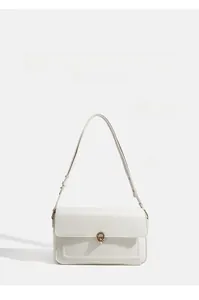 Detail view of a white leather shoulder bag with gold circular lock and adjustable strap