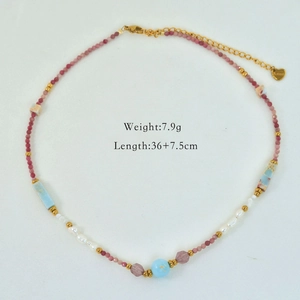 Dettaglio collana di perle con pietre rosa e ciondolo a cuore dorato su sfondo bianco