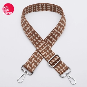 Detail of silver-tone hardware buckle on brown houndstooth pattern wide bag strap