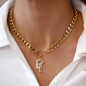Detail of gold Cuban chain necklace with sparkling rhinestone lock and key charms