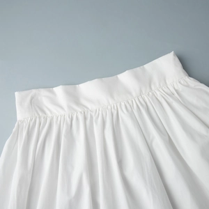 Détail de la taille d'une jupe longue blanche en coton avec plis élégants et finitions soignées