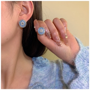Macro detail of retro blue enamel earrings and ring set featuring central pearl flowers