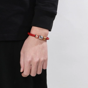 Braided red leather bracelet with gold, silver and rose gold metal beads on model wrist