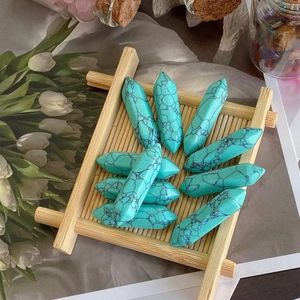 Macro shot of turquoise double-pointed hexagonal pillars on a bamboo tray for healing crystal