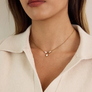 Detail of 18K gold necklace featuring teardrop and marquise zircon pendants on a model