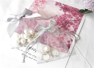 Detail of grey and white organza jewelry bags with ribbons and decorative pearls
