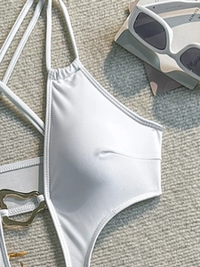 Close-up of white cutout swimsuit with golden heart-shaped ring and elegant halter straps