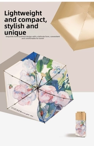 Detail of artistic floral pattern and luxury gold handle on compact flat folding umbrella