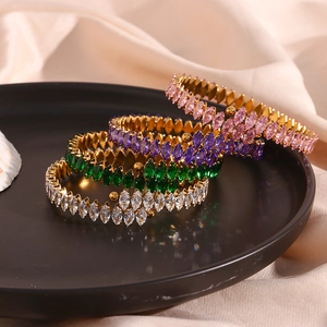 Close-up of golden bangle bracelets with pink, purple, green, and white marquise zircons