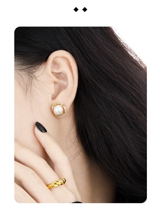 Close-up of elegant gold flower diamond pearl earrings and twisted ring set on a model