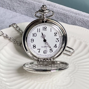 Detail of vintage Alice quartz pocket watch in silver on decorative white plate