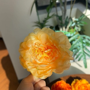 Close-up of yellow silk peony hair clip showing delicate petal texture and realistic stamens