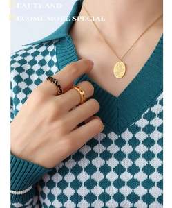 Dettaglio della collana con rosa vintage e anelli con pietre nere sulla modella