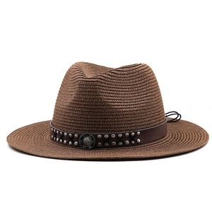 Close-up of brown straw cowboy hat with leather band and studded metal buckle detail