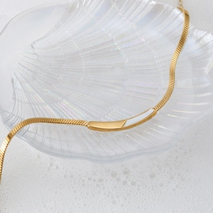 Golden stainless steel shell pendant necklace on white seashell with pearl backdrop